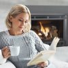 Woman reading next to a gas fireplace